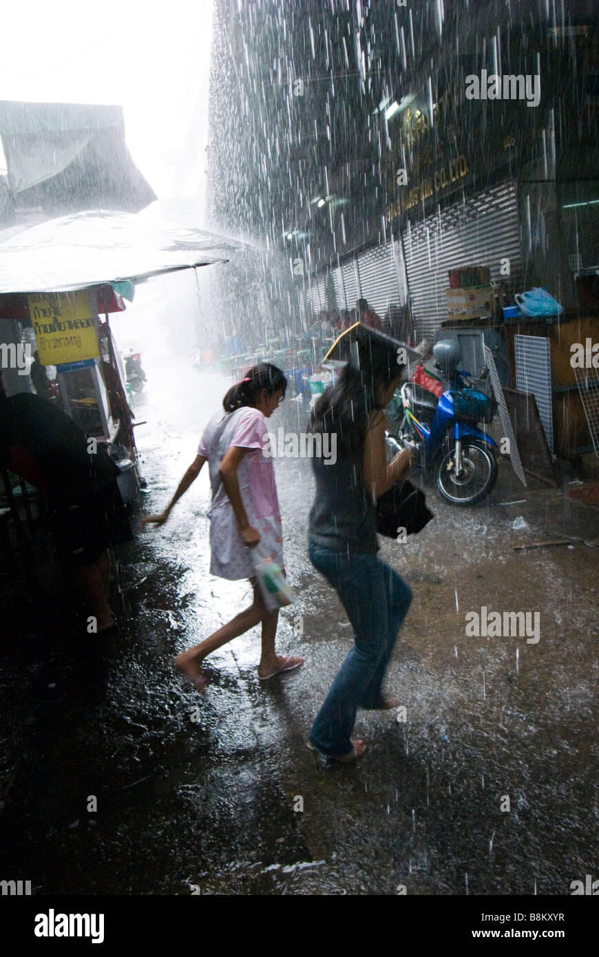 People caught in monsoon downpour in alleyway Chinatown central Bangkok Thailand Stock Photo