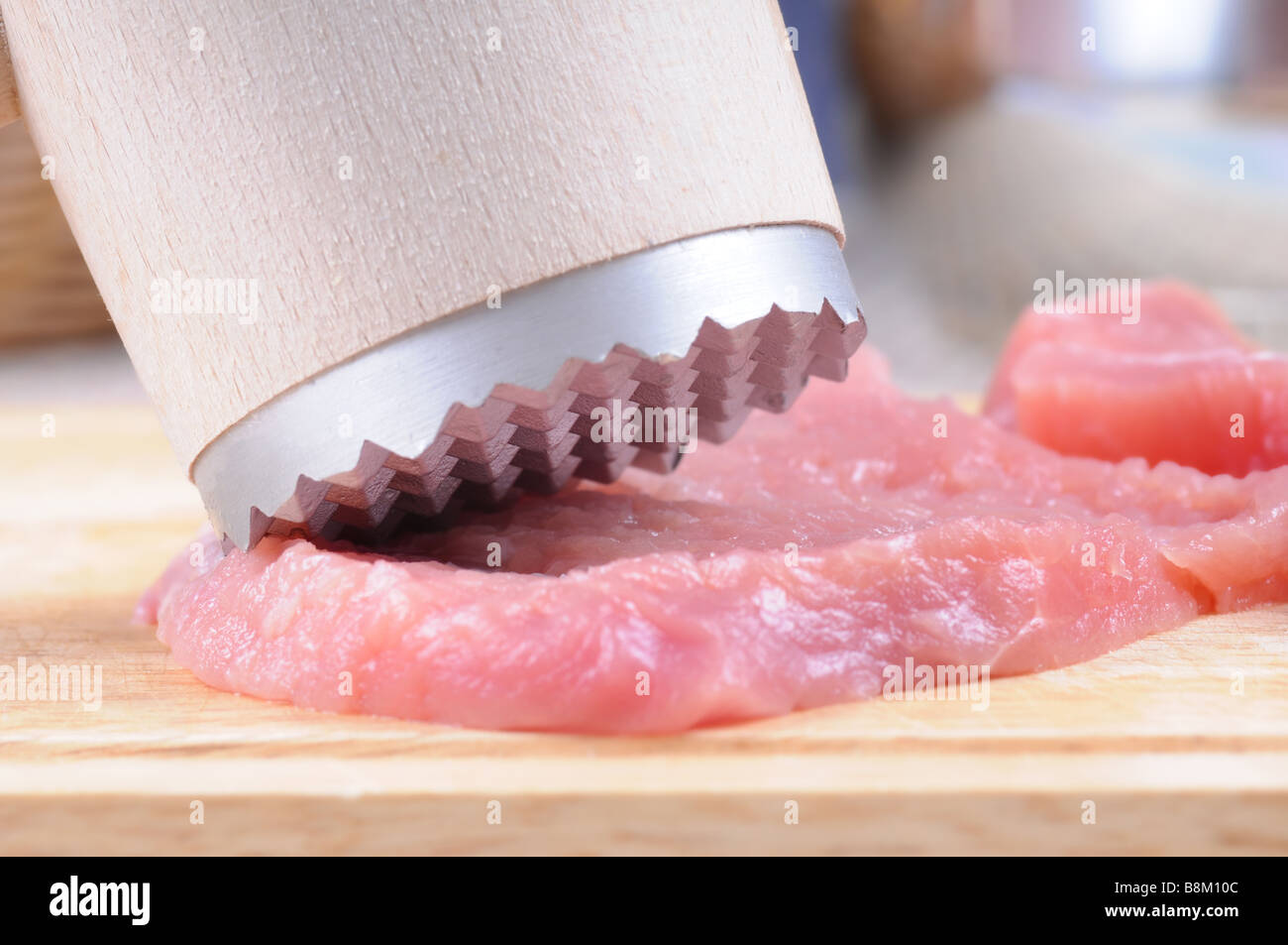 Tenderization of fresh pork steaks on wooden chopping board. Detail with small DOF. Stock Photo