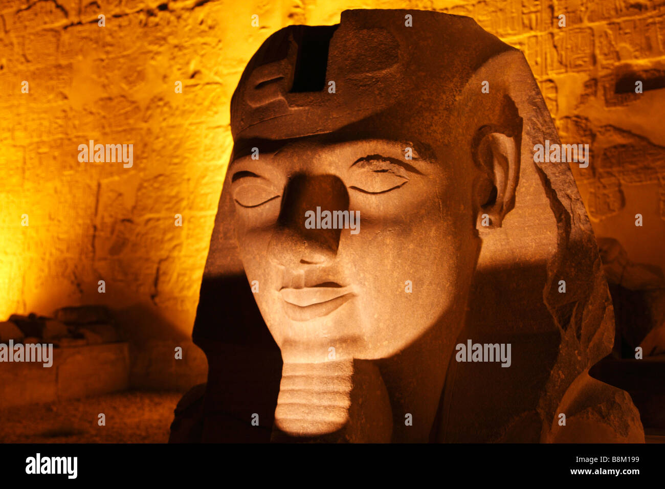 Ramses II head sculpture at entrance to Luxor Temple illuminated at ...