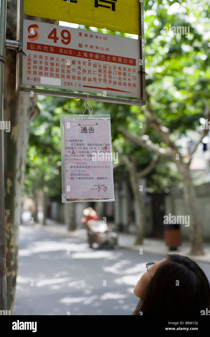 Reading an announcement at a bus stop in Shanghai's colonial French Concession. Stock Photo
