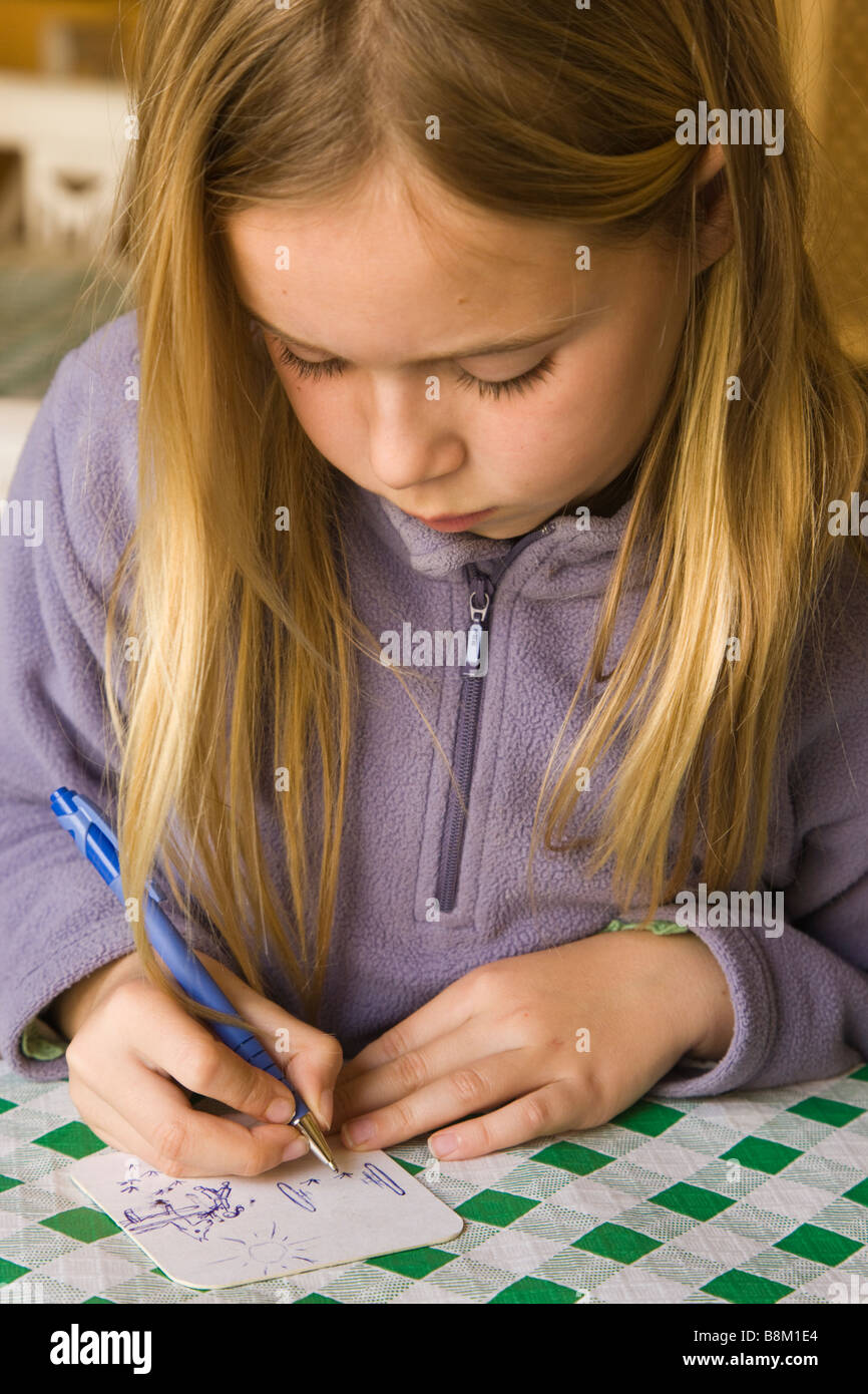 Eight year old girl concentrating hard as she draws a picture Stock Photo