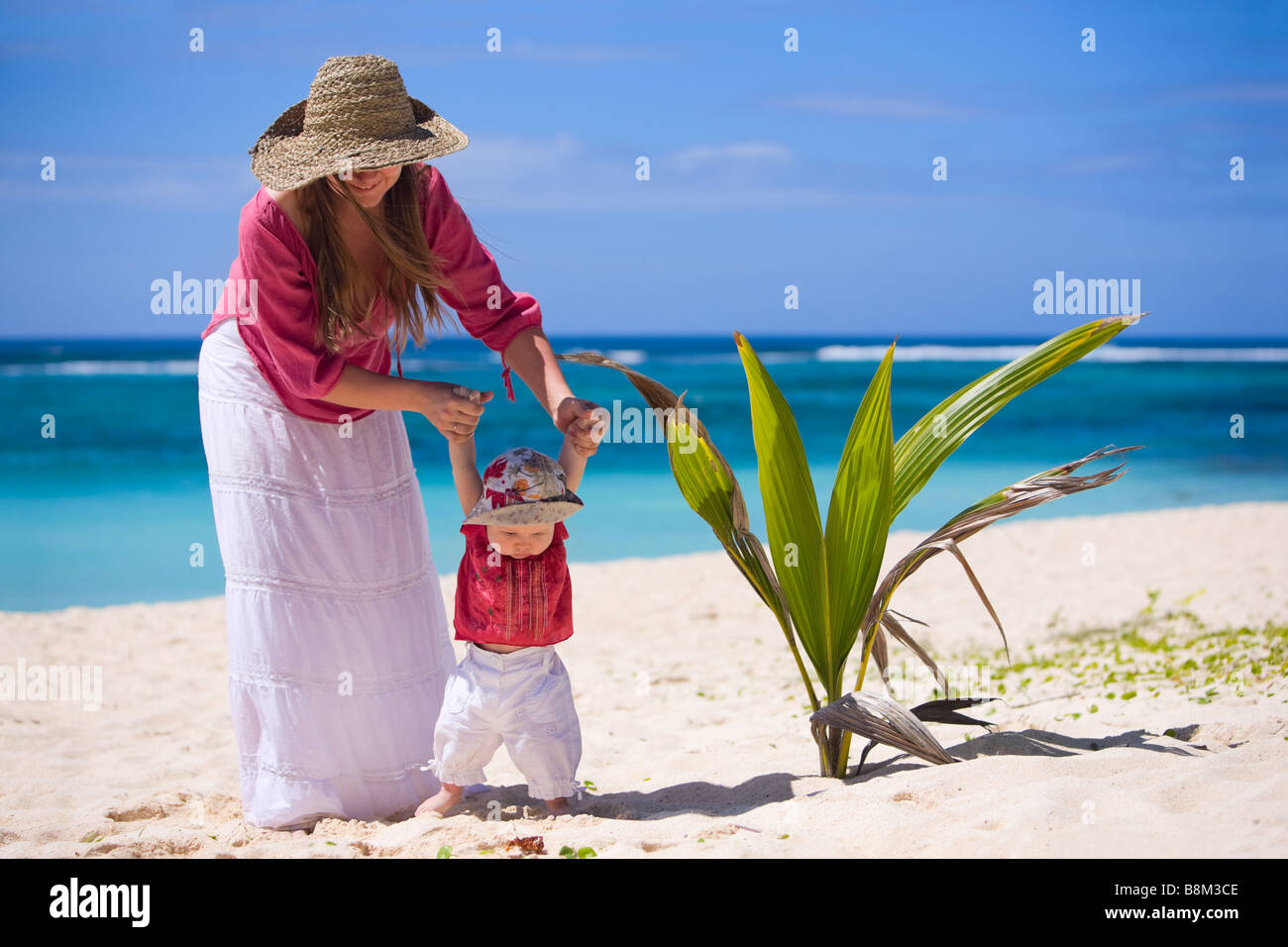 Young mother and baby girl on white sand tropical beach Stock Photo