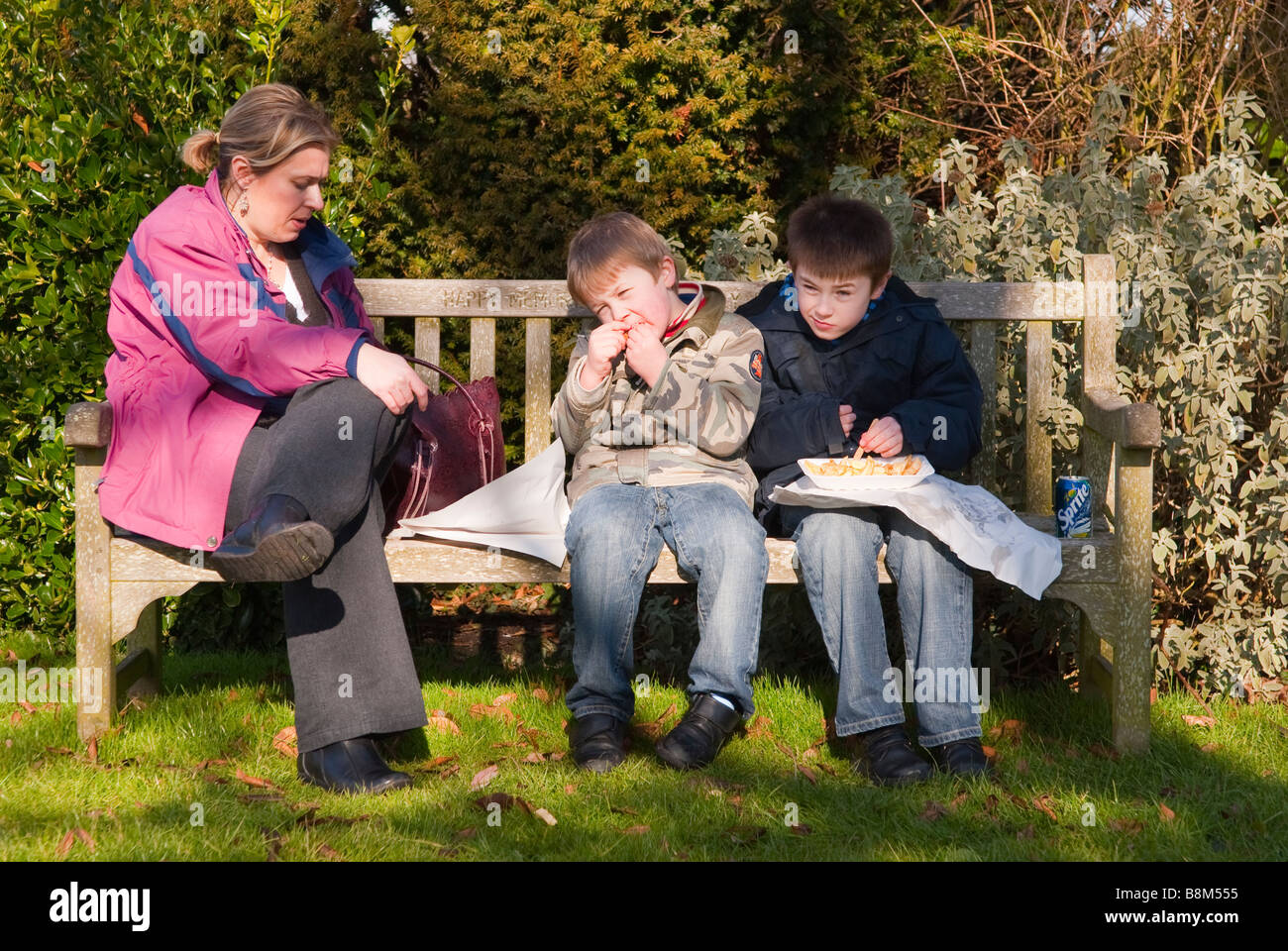 A family eating fish & chips on a bench outside in the Uk Stock Photo