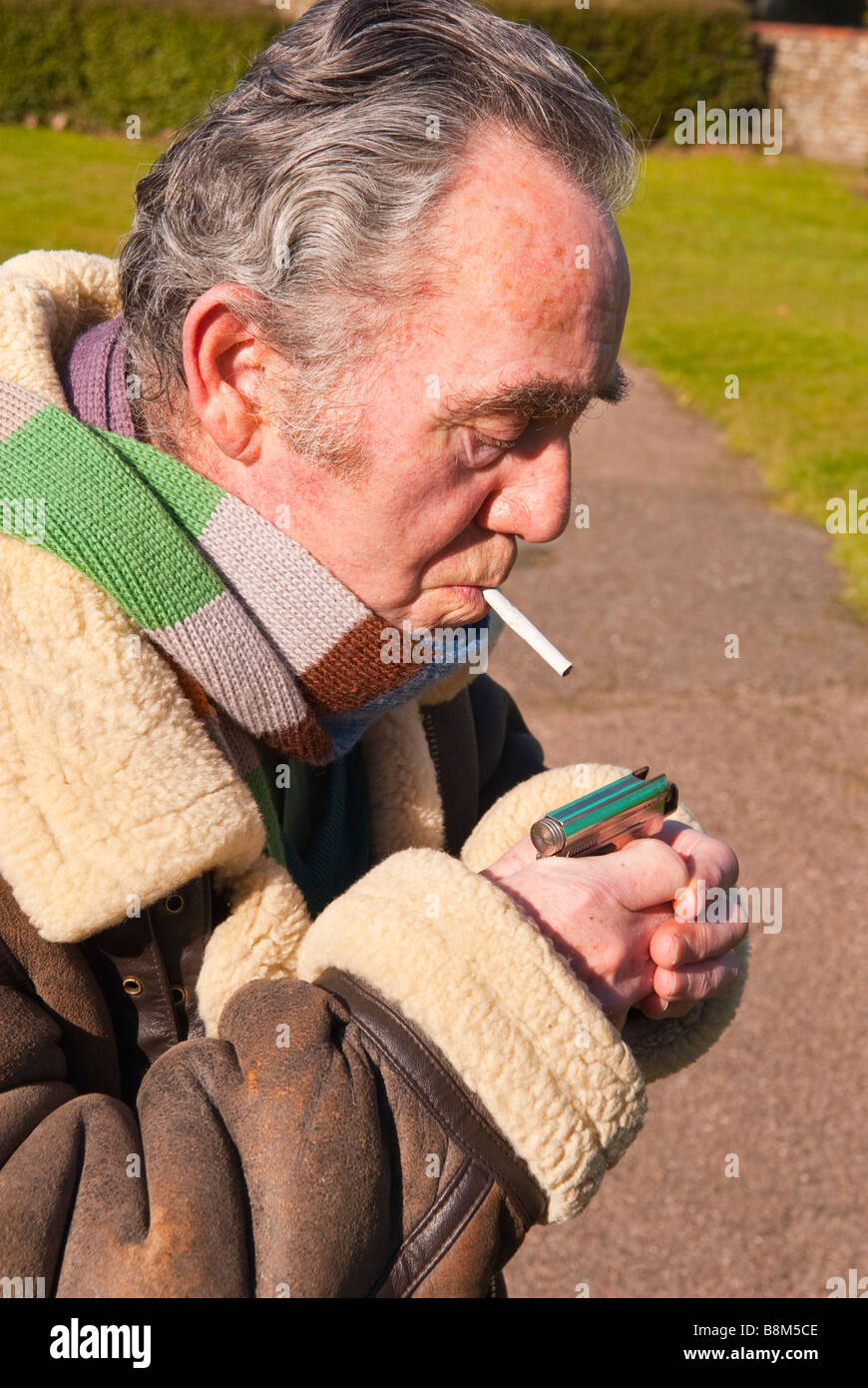 Elderly man lighting his roll up cigarette outdoors ready for smoking Stock Photo