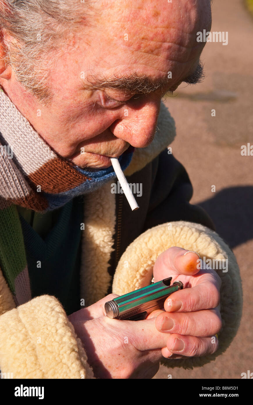 Elderly man lighting his roll up cigarette outdoors ready for smoking Stock Photo