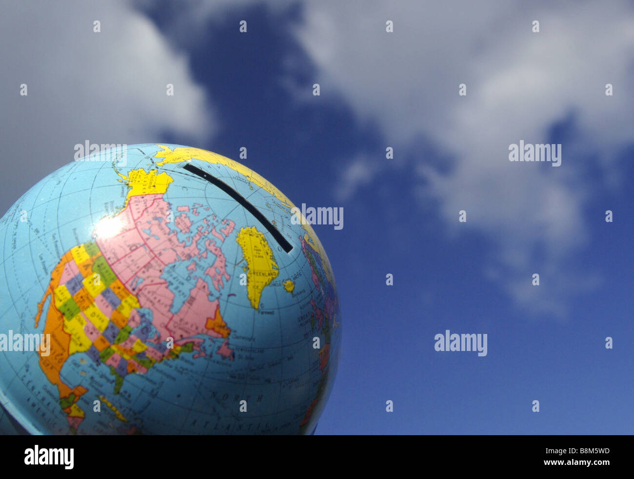 World Globe / Global money box with blue sky background. Stock Photo