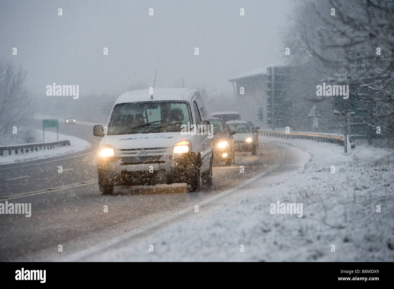 Cars driving slowly on a snowy road in winter in England Stock Photo