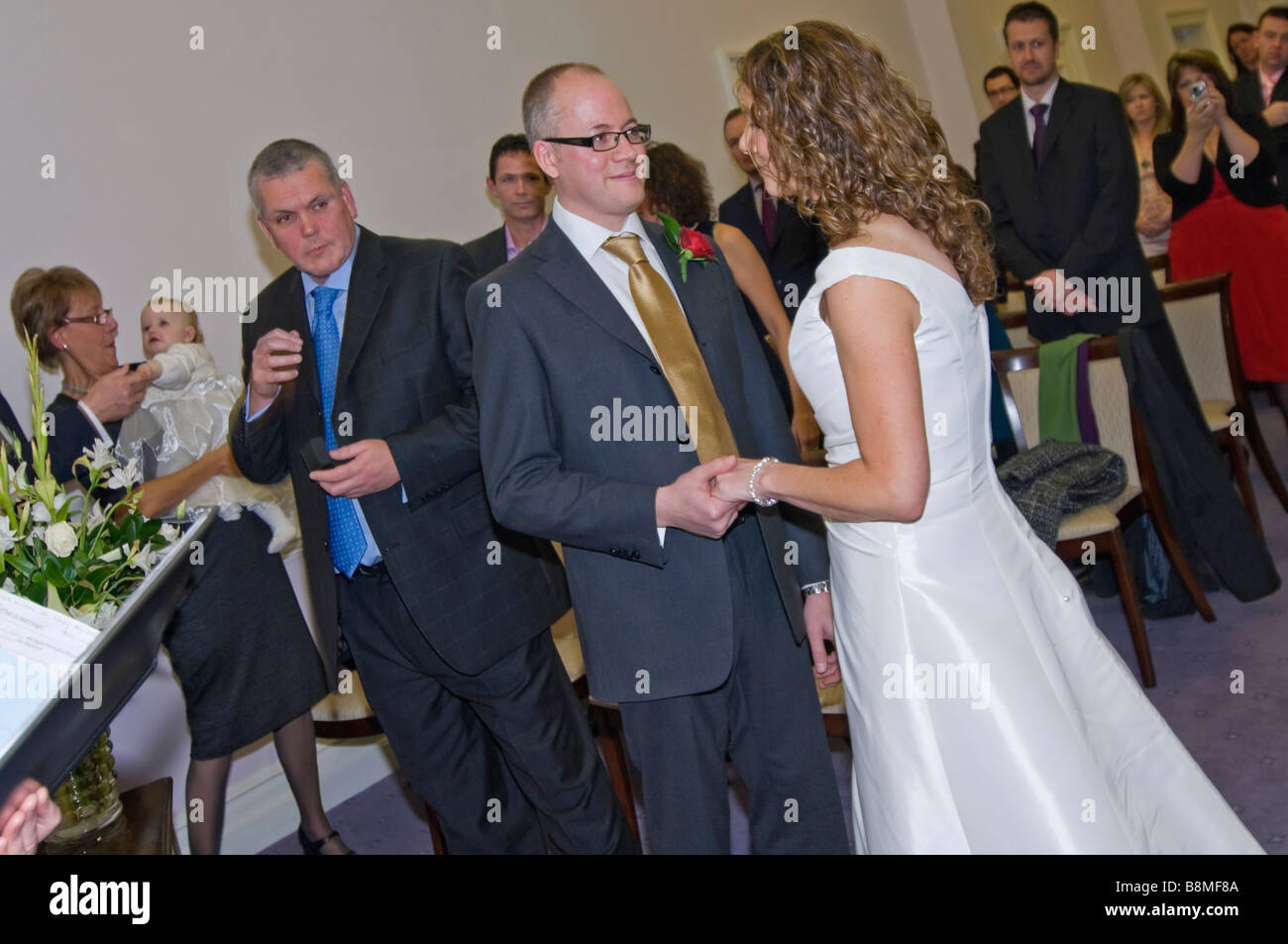 Horizontal wide angle portrait of a bride and groom standing together saying their vows and exchanging rings at a civil ceremony Stock Photo