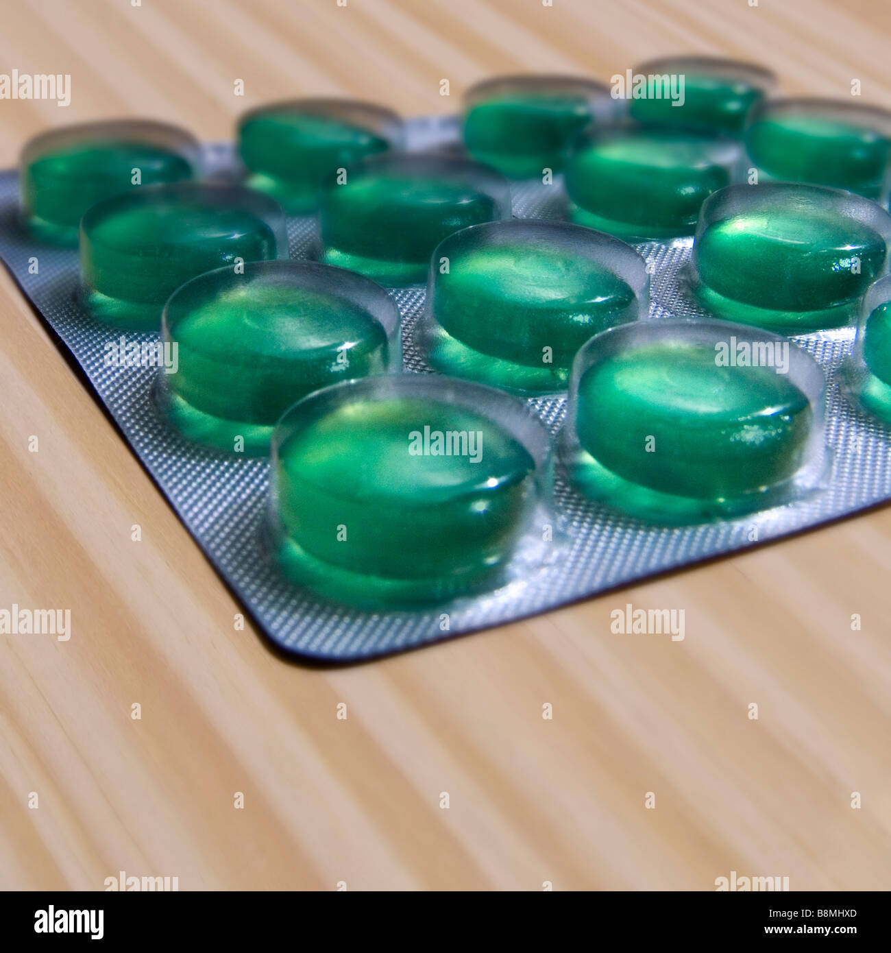 Green Throat Lozenges in a Blister Pack on a Wooden Surface Stock Photo