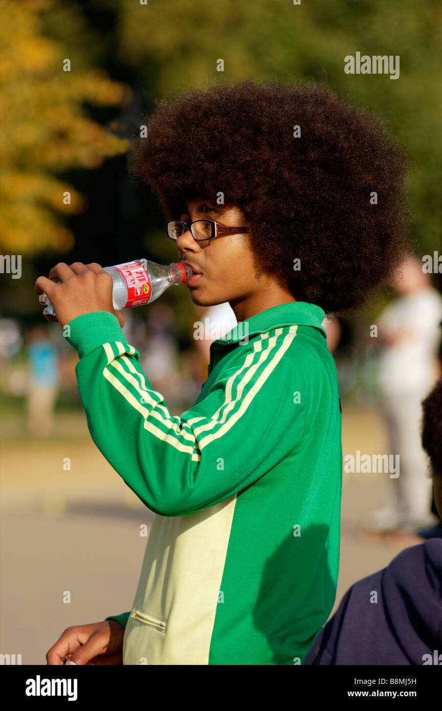 A young black man with a huge afro drinking a bottle of water 