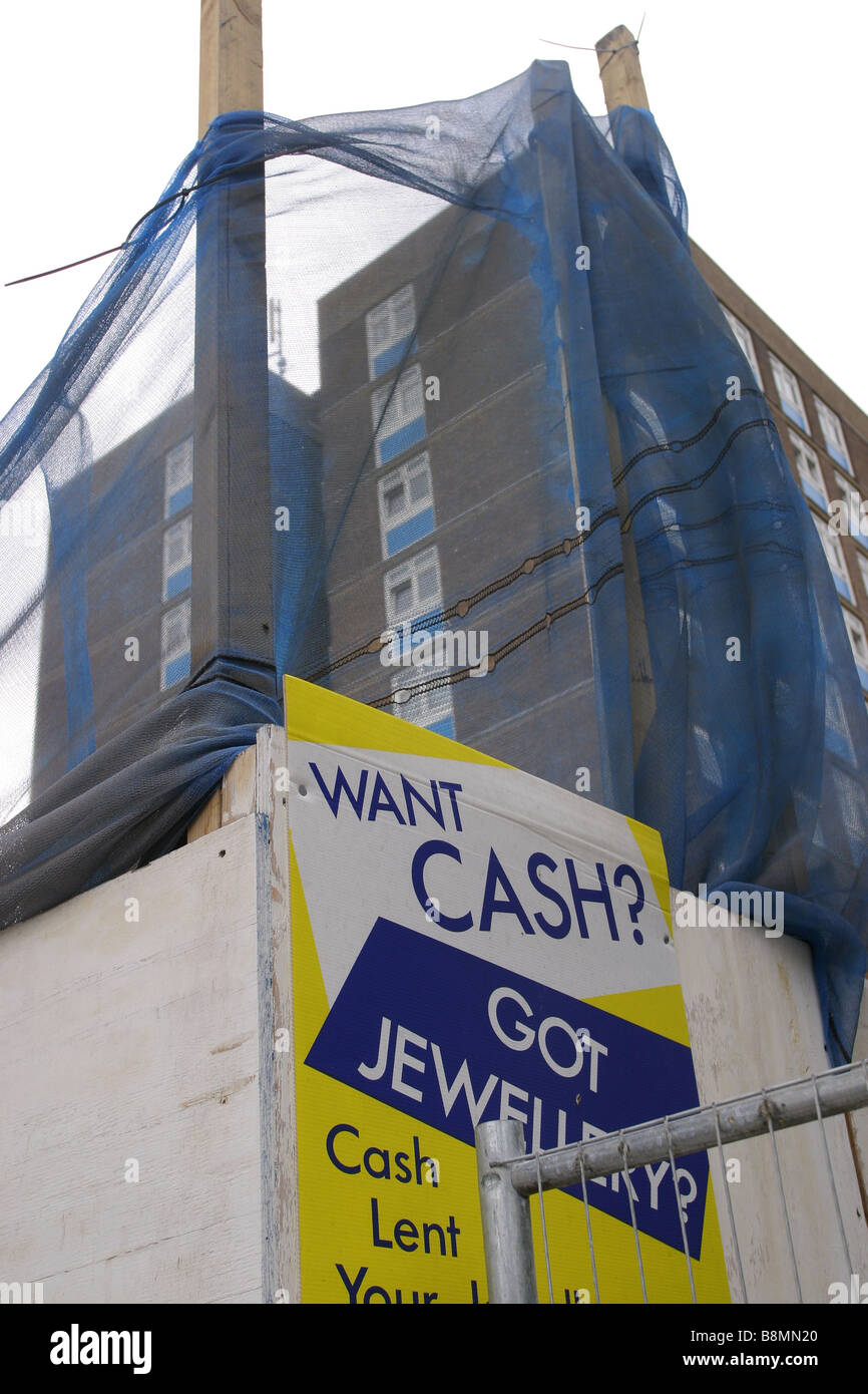 Sign for pawnbroker in front of building site and a block of council flats. Stock Photo