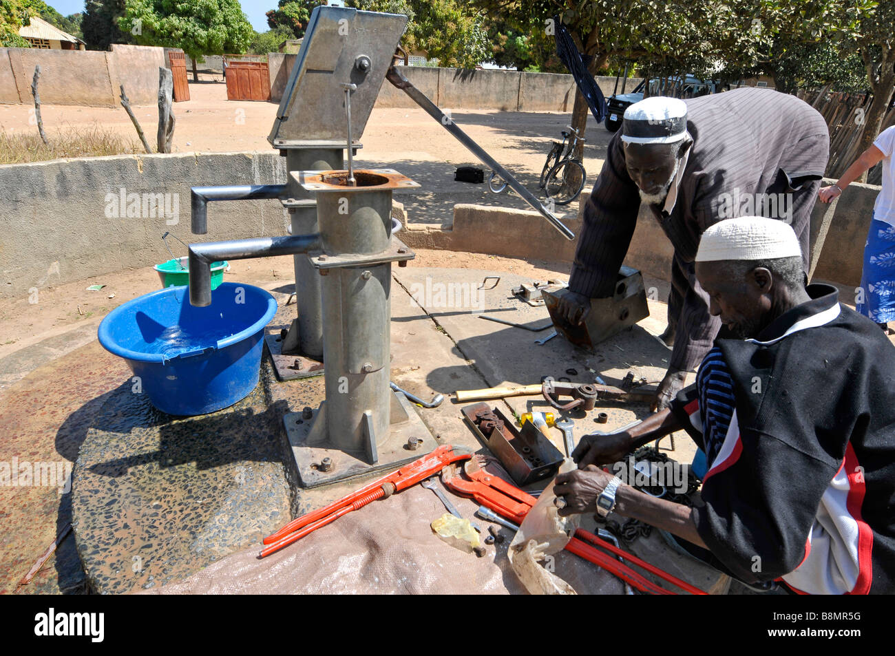Men repair a water pump in a village in The Gambia, West Africa Stock