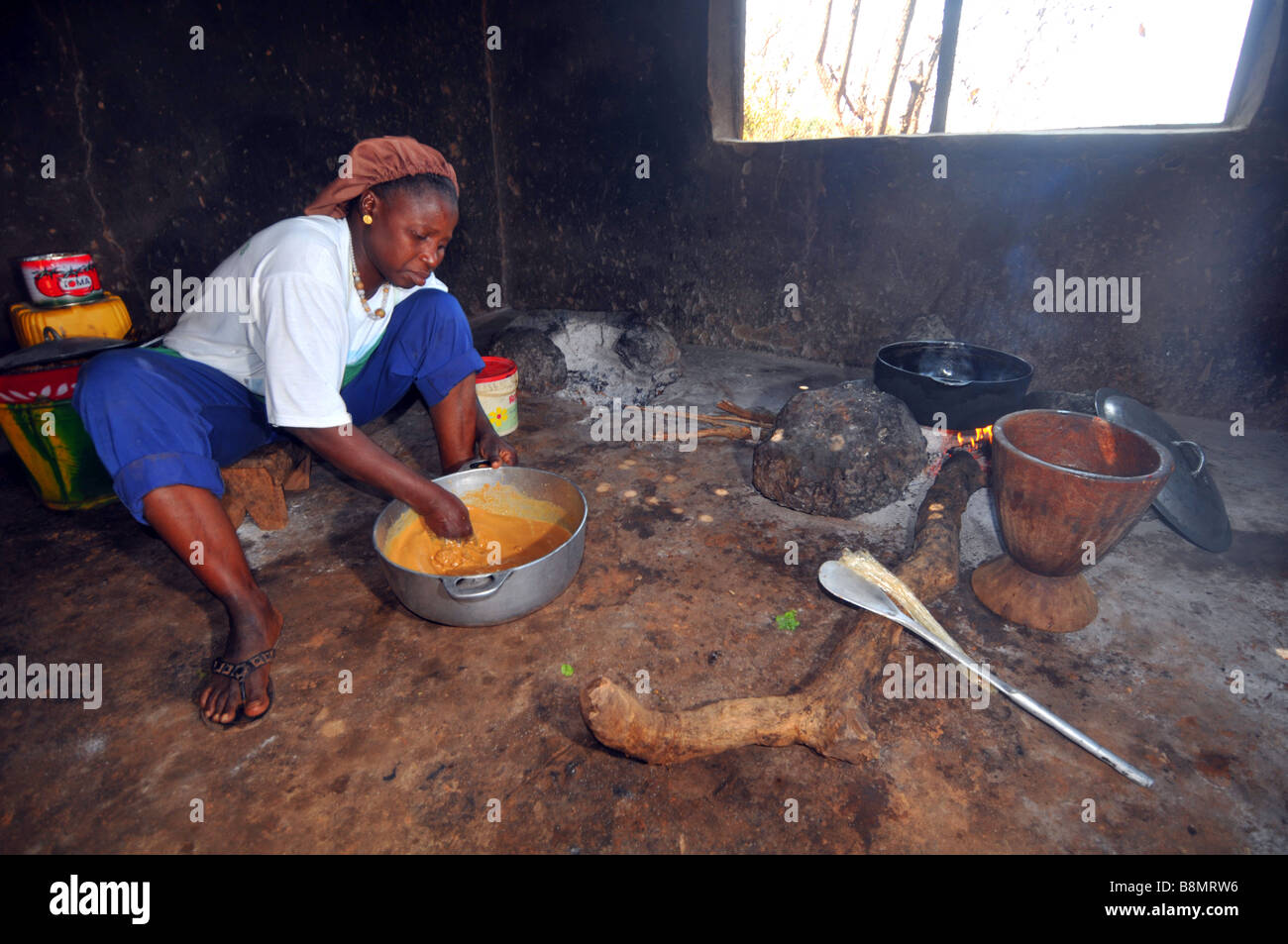 Woman cooking over an open fire in her basic rural village kitchen, The Gambia, West Africa Stock Photo