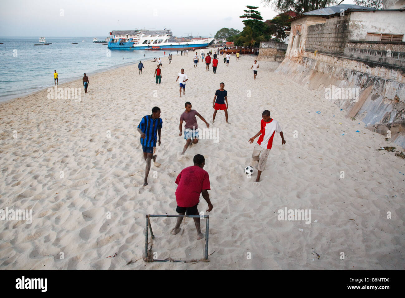 people play football match on the beach in Stone Town in Zanzibar, Tanzania Stock Photo