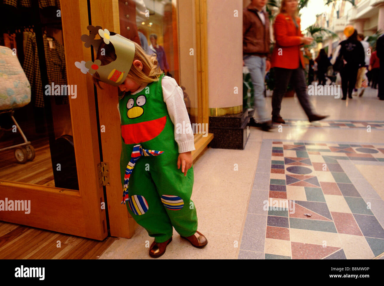 Lakeside Shopping Centre Thurrock Essex UK A tired girl wearing a Burger King crown rests outside a shopfront Stock Photo