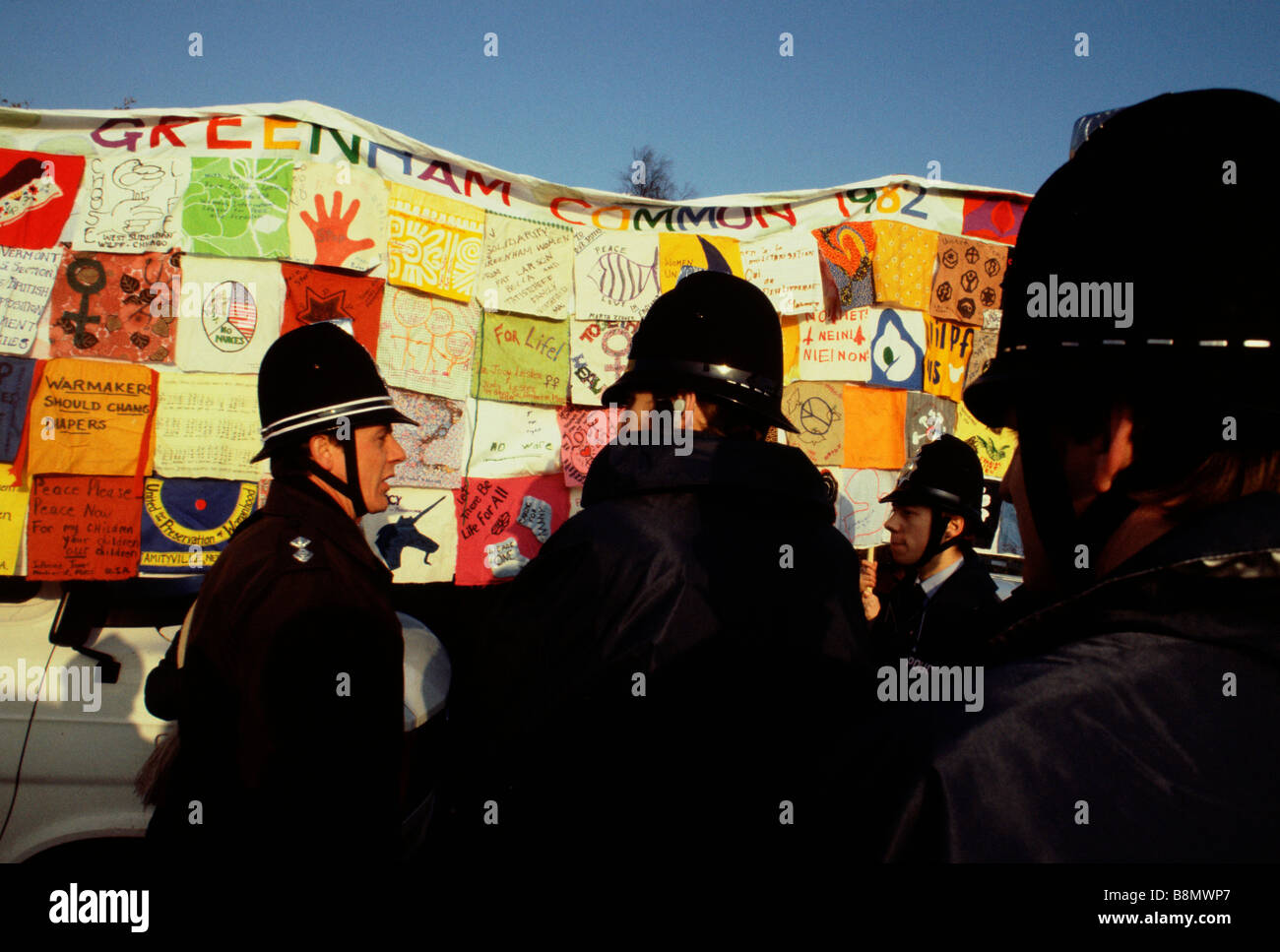 Greenham Berkshire UK December 1982 Protesters at the Greenham Common Women s Peace Camp carry a patchwork quilt of CND messages Stock Photo