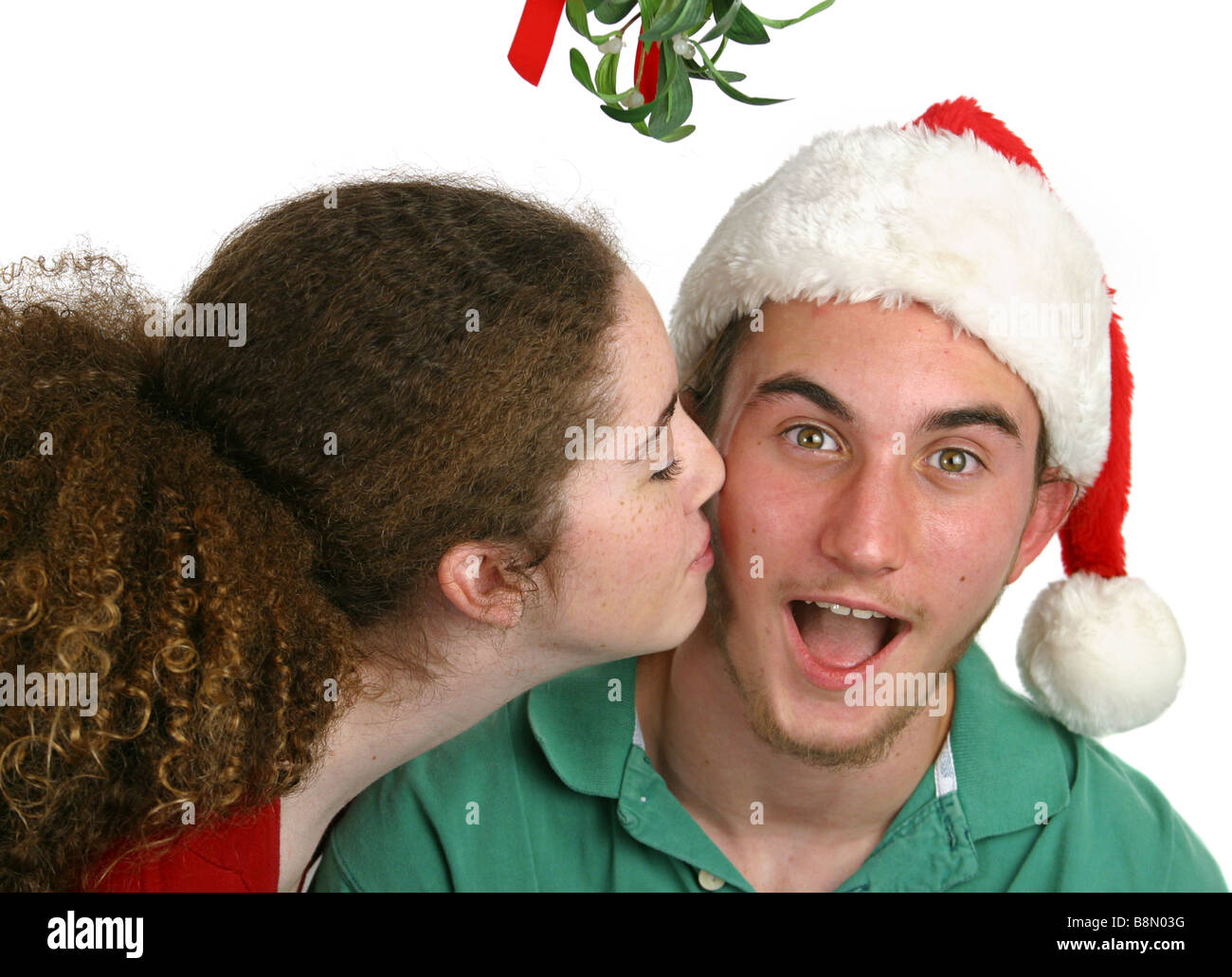 A teen girl surprising a teen boy with a kiss under the mistletoe Isolated ...