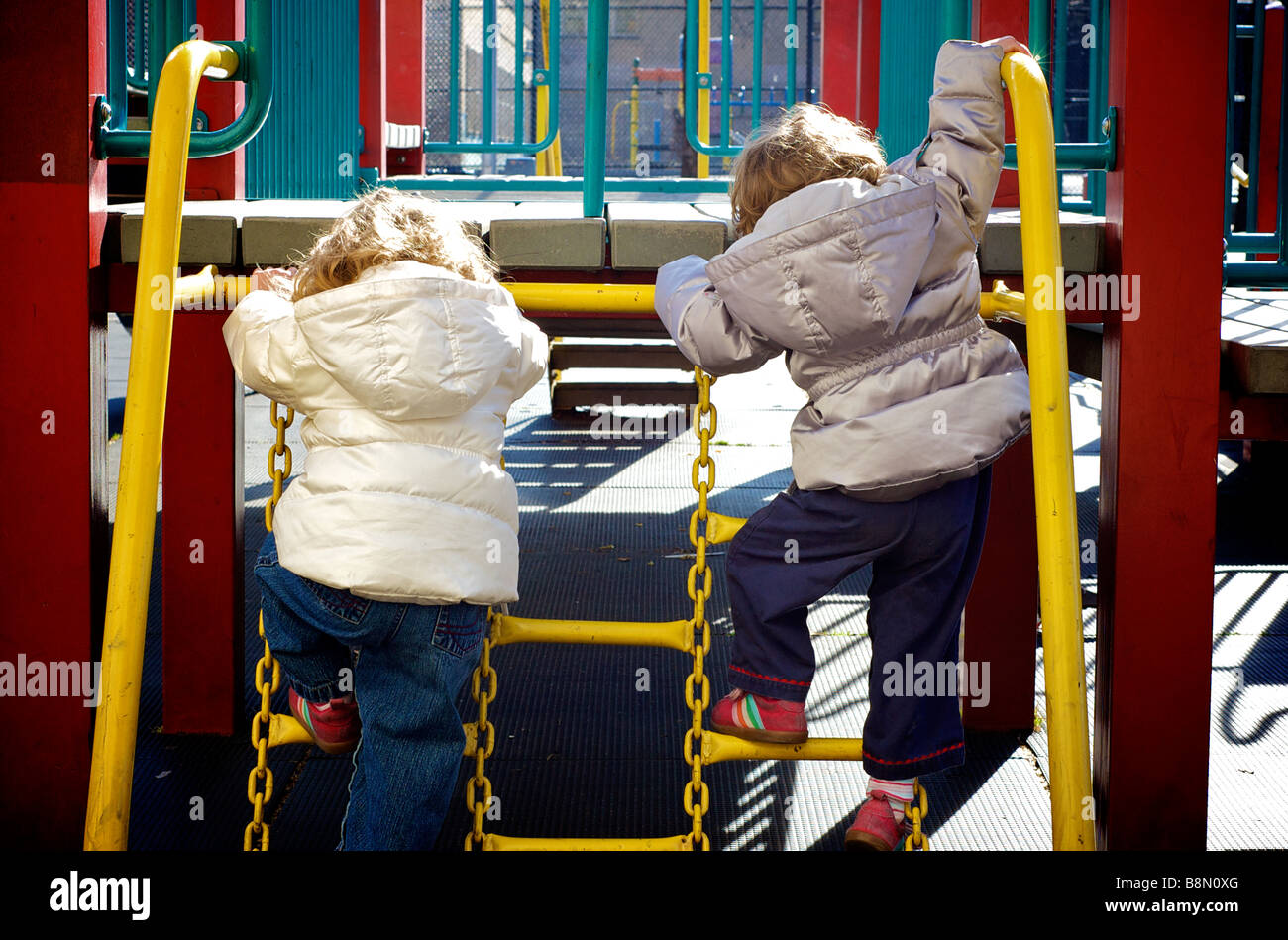 Two Children Climbing Jungle Gym at Urban Playground Stock Photo