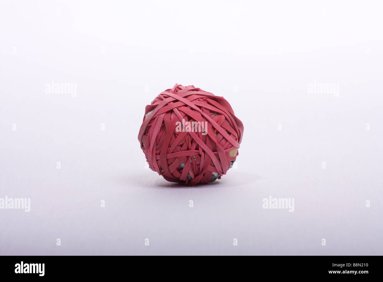 ball of newspaper covered in red rubber bands against white background