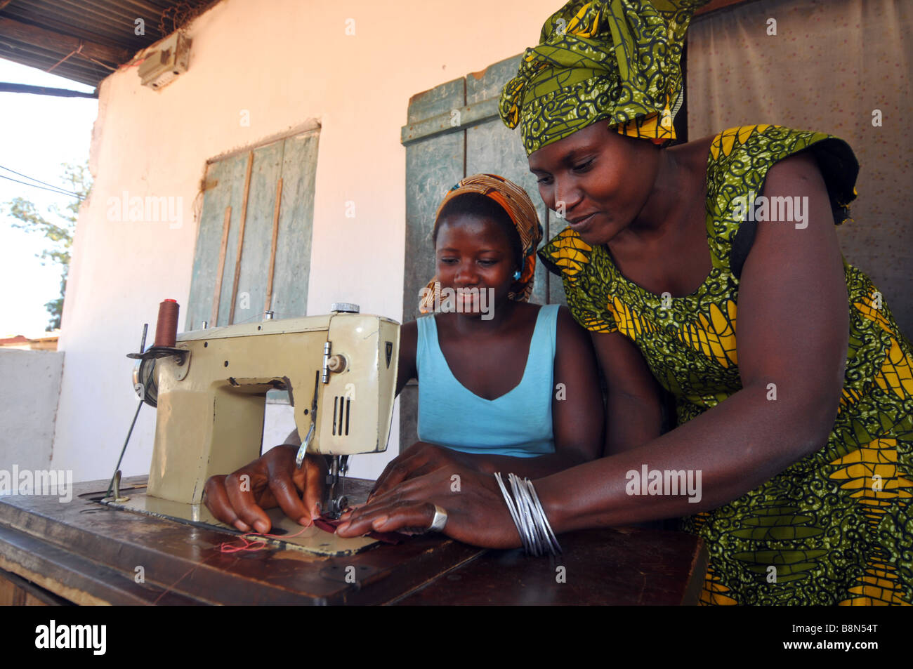 Woman teaching how to use a "sewing machine" to women in The Gambia