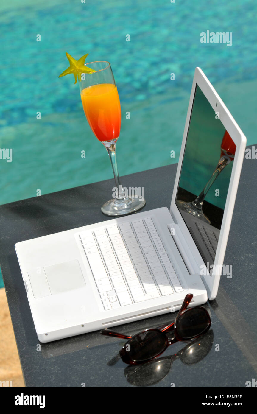 Laptop computer and cocktail by pool Stock Photo