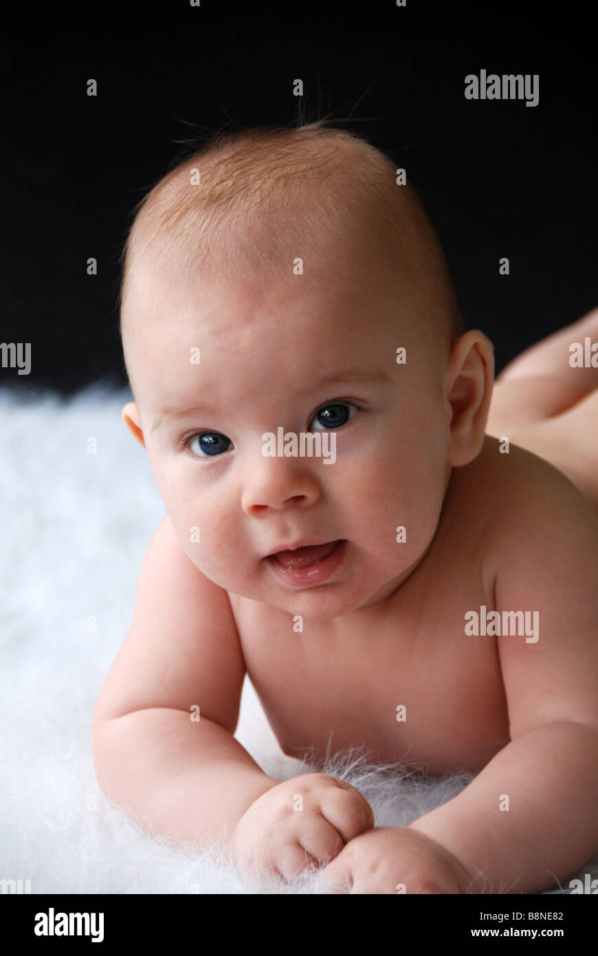 Happy baby laying naked on a rug Stock Photo
