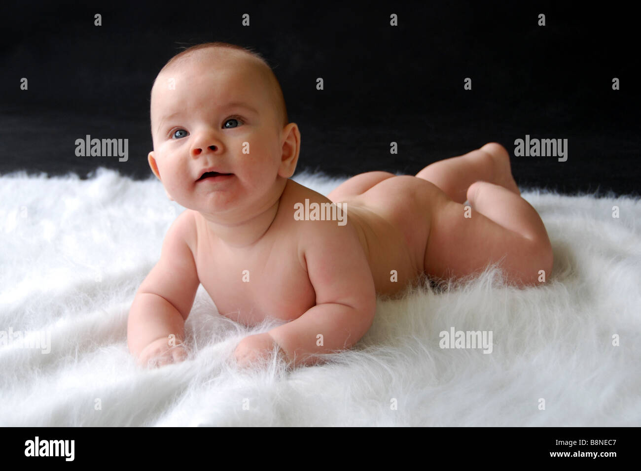 Happy baby laying naked on a rug Stock Photo