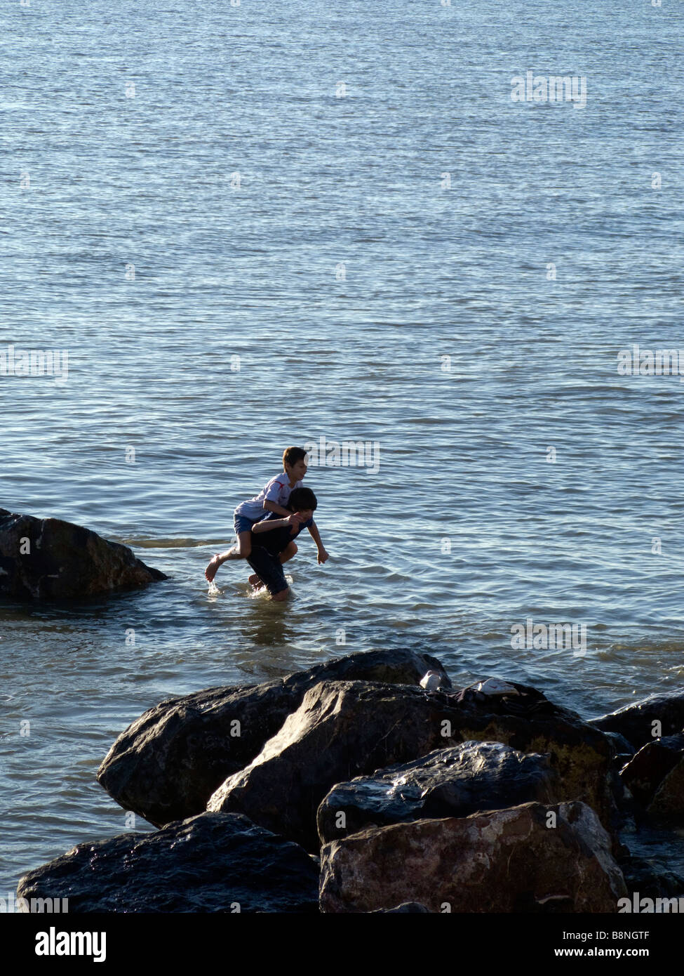 Piggy back ride through the surf. Stock Photo