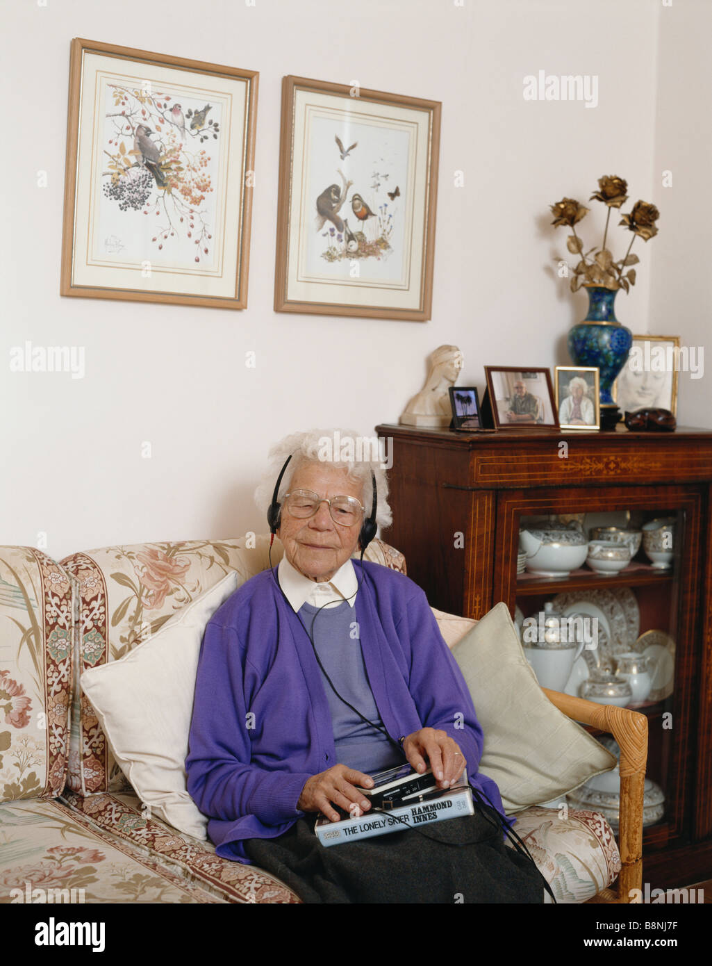 Elderly blind lady at home listening to a talking book on a Sony Walkman, UK Stock Photo