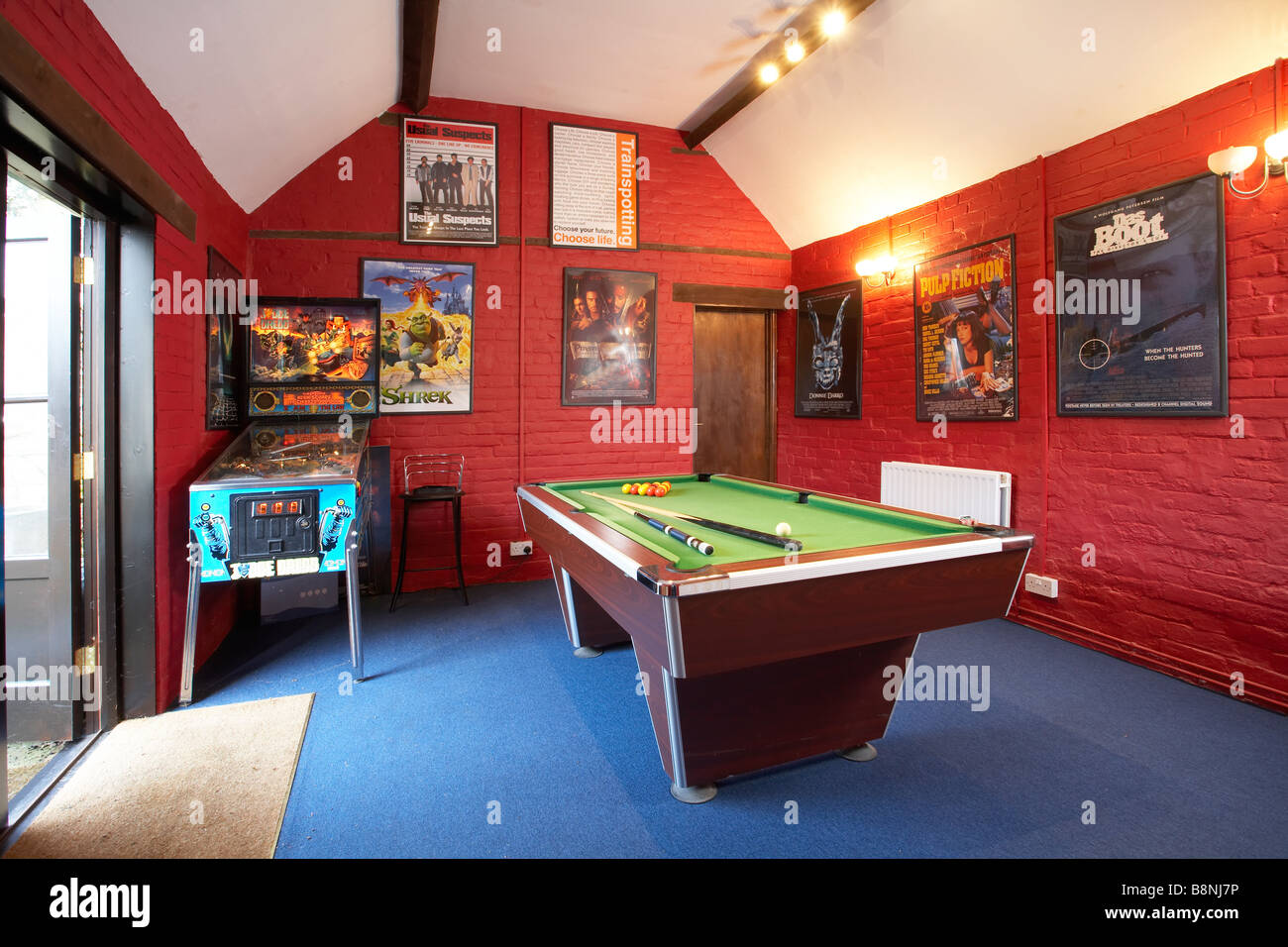 Games room interior red pool table pinball machine film posters Stock Photo  - Alamy