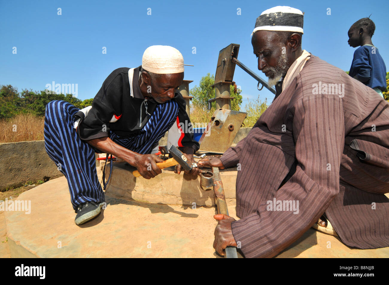 Men repair a water pump in a village in The gambia, West Africa Stock