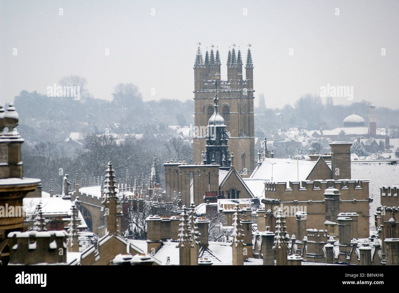 Looking across the rooves of Oxford Colleges towards Magdalen College Tower in snow and winter Stock Photo