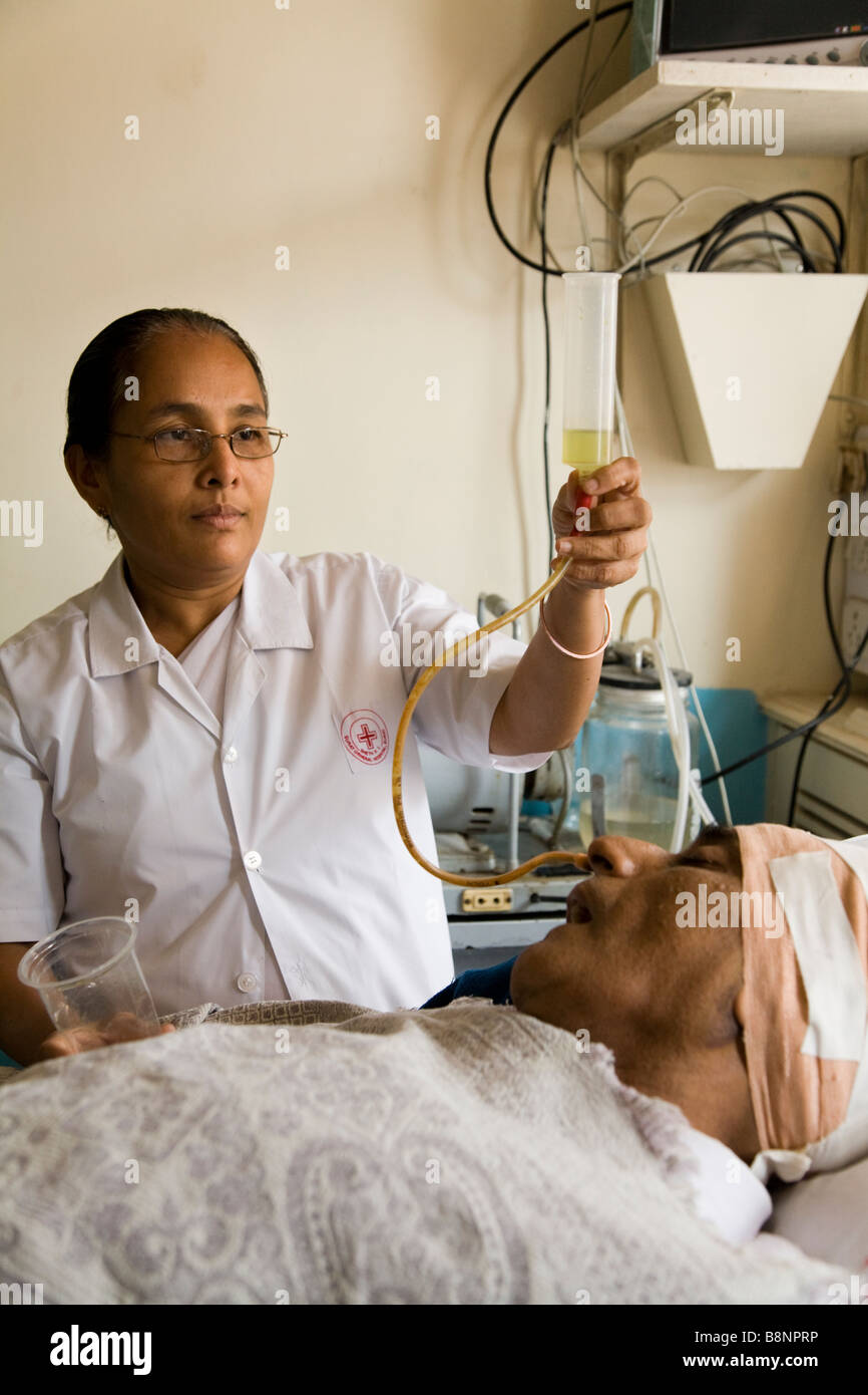 Nurse feeding a very sick patient though a tube in intensive care ward