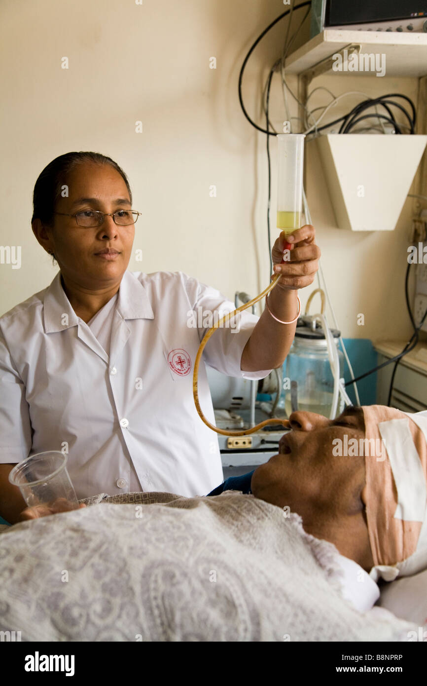Nurse feeding a very sick patient though a tube in intensive care ward of the New Civil Hospital, Surat. Gujarat. India. Stock Photo