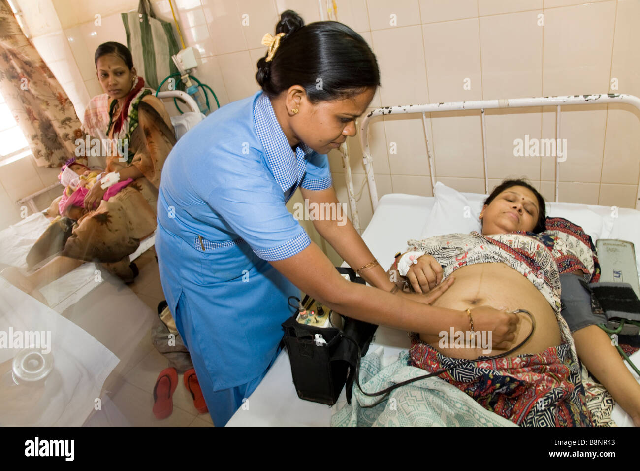 Maternity nurse / midwife examines heavily pregnant woman patient in the maternity ward of the New Civil Hospital, Surat. Gujarat. Stock Photo