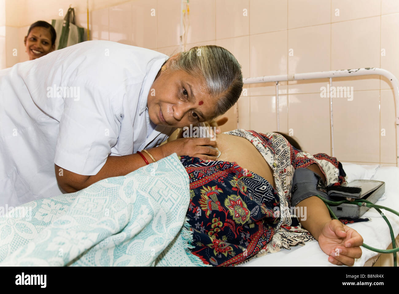Maternity nurse listens to / monitoring heart unborn baby of pregnant woman in the maternity ward of the New Civil Hospital, Surat. Gujarat. India. Stock Photo