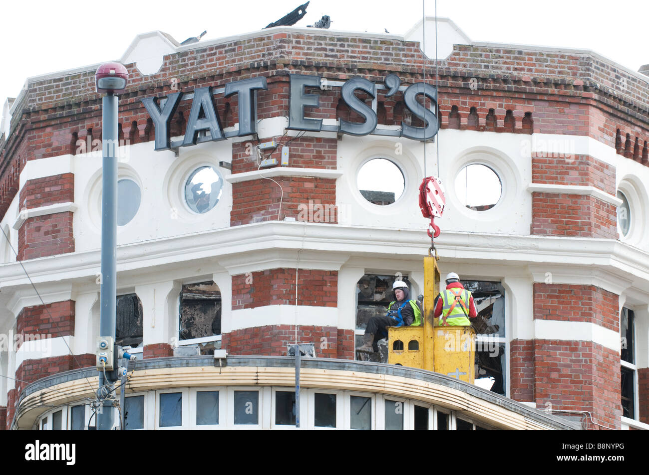 Two construction workers examine the fire damage to Yates's Wine Lodge in Blackpool, England Stock Photo