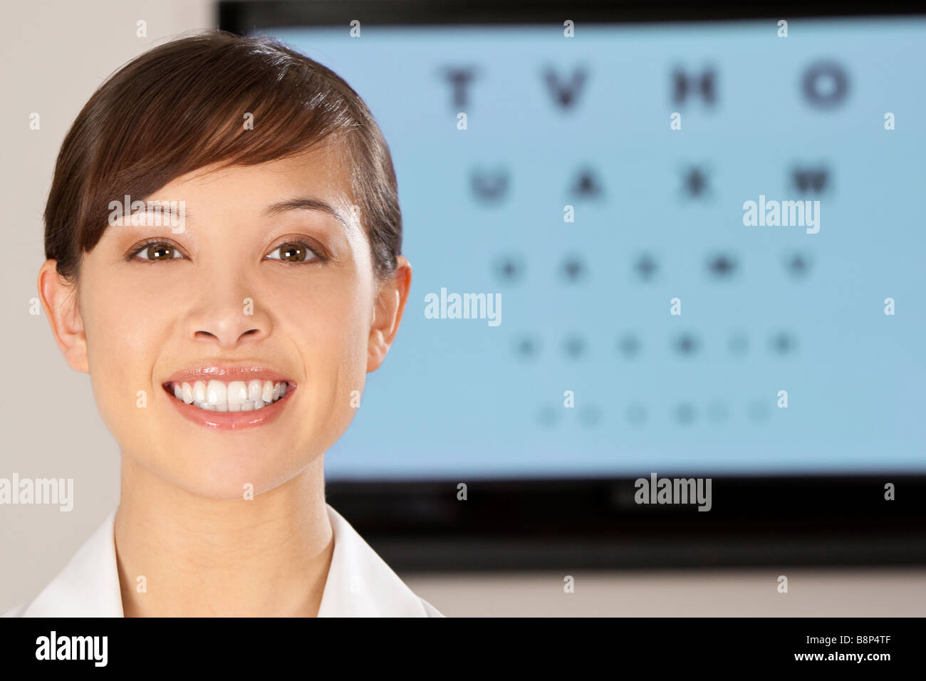 A beautiful female optician shot with an electronic eye test chart out
