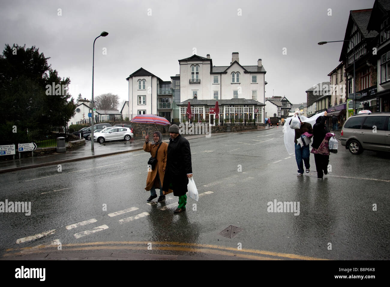 Asian Tourists in the rain in Bowness on Windermere with the Royal & Costa's in the background