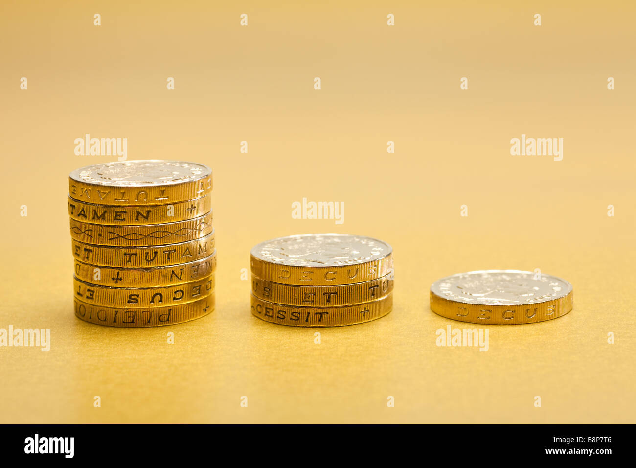Decreasing stacks of £1 one pound coins sterling on gold background Stock Photo