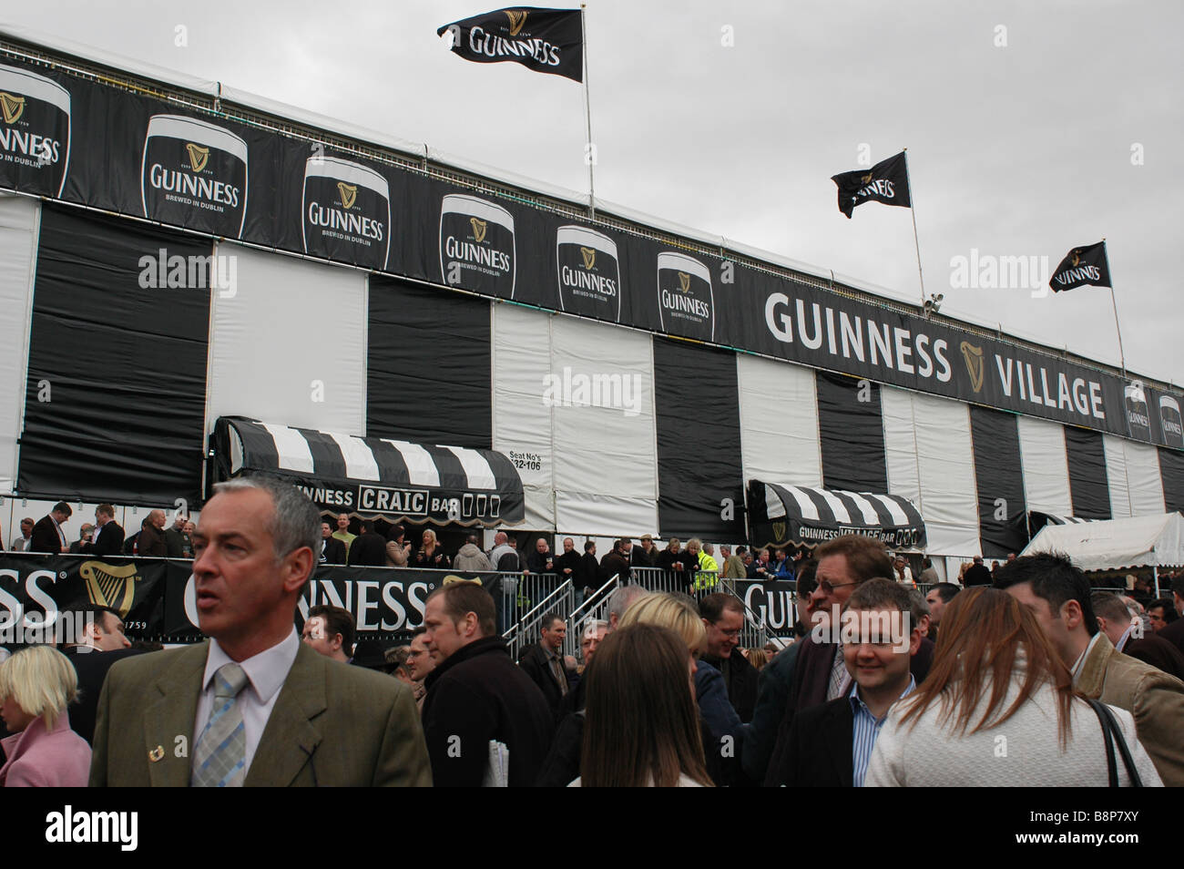 Cheltenham Gold Cup Guinness Village, crowded fans drinking amongst the flags Stock Photo