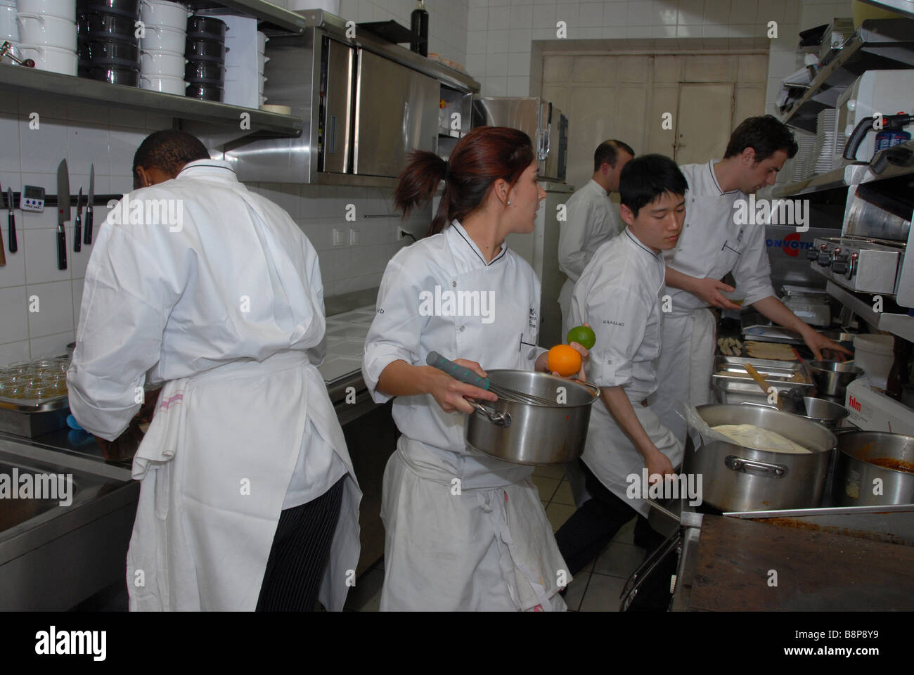A brigade of chefs preparing meals in a busy kitchen of the Cafe de la Cloche in the old town of Lyon,France Stock Photo