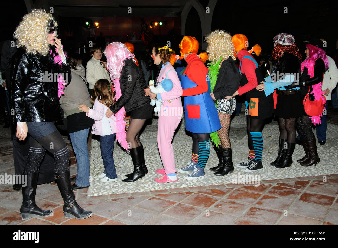 Girls in fancy dress dance the conga during a spanish carnival on the