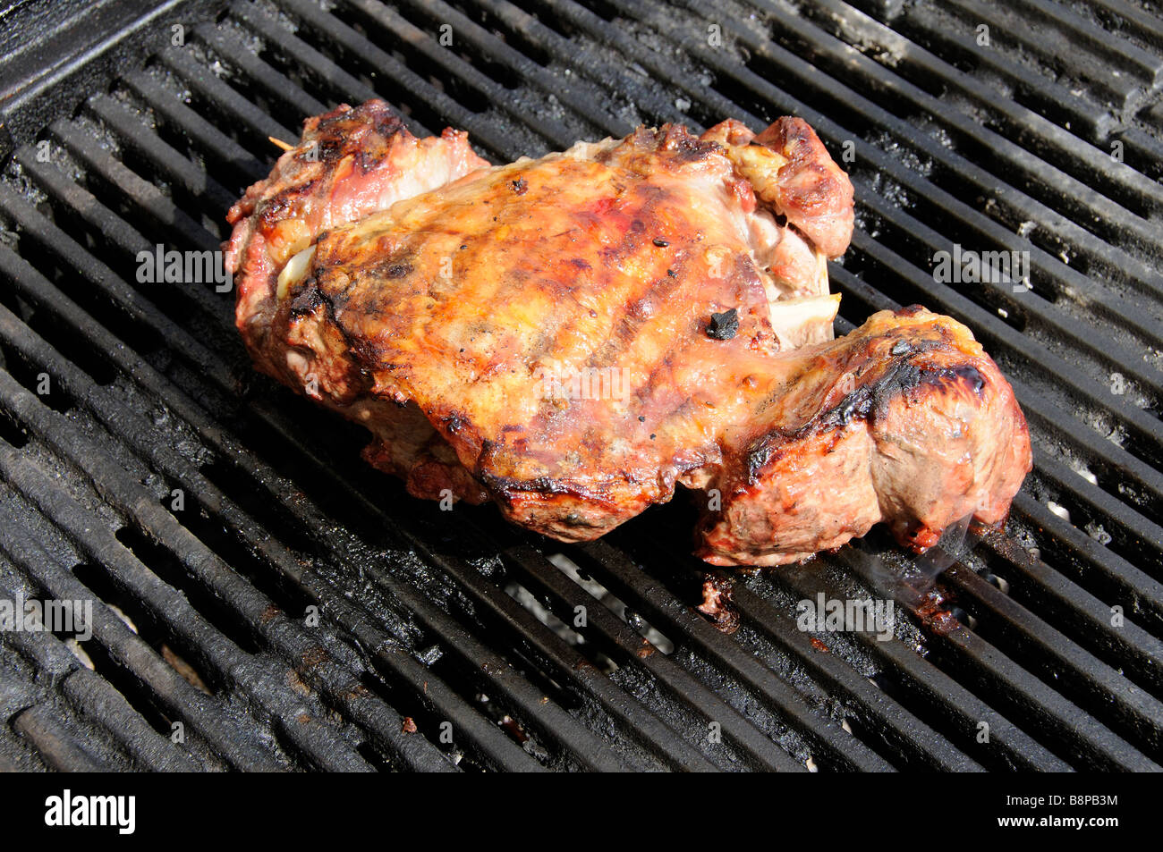 Marinaded boned leg of lamb cooks on a hot barbecue grill Stock Photo