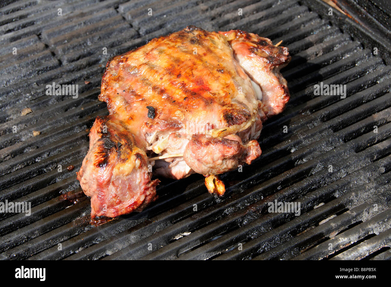 Marinaded boned leg of lamb cooks on a hot barbecue grill Stock Photo