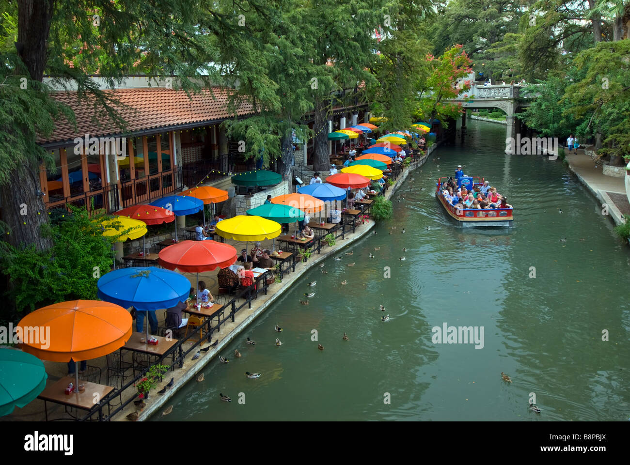 San Antonio River Walk riverwalk row of blue yellow orange umbrellas of outdoor cafes line river bank Stock Photo