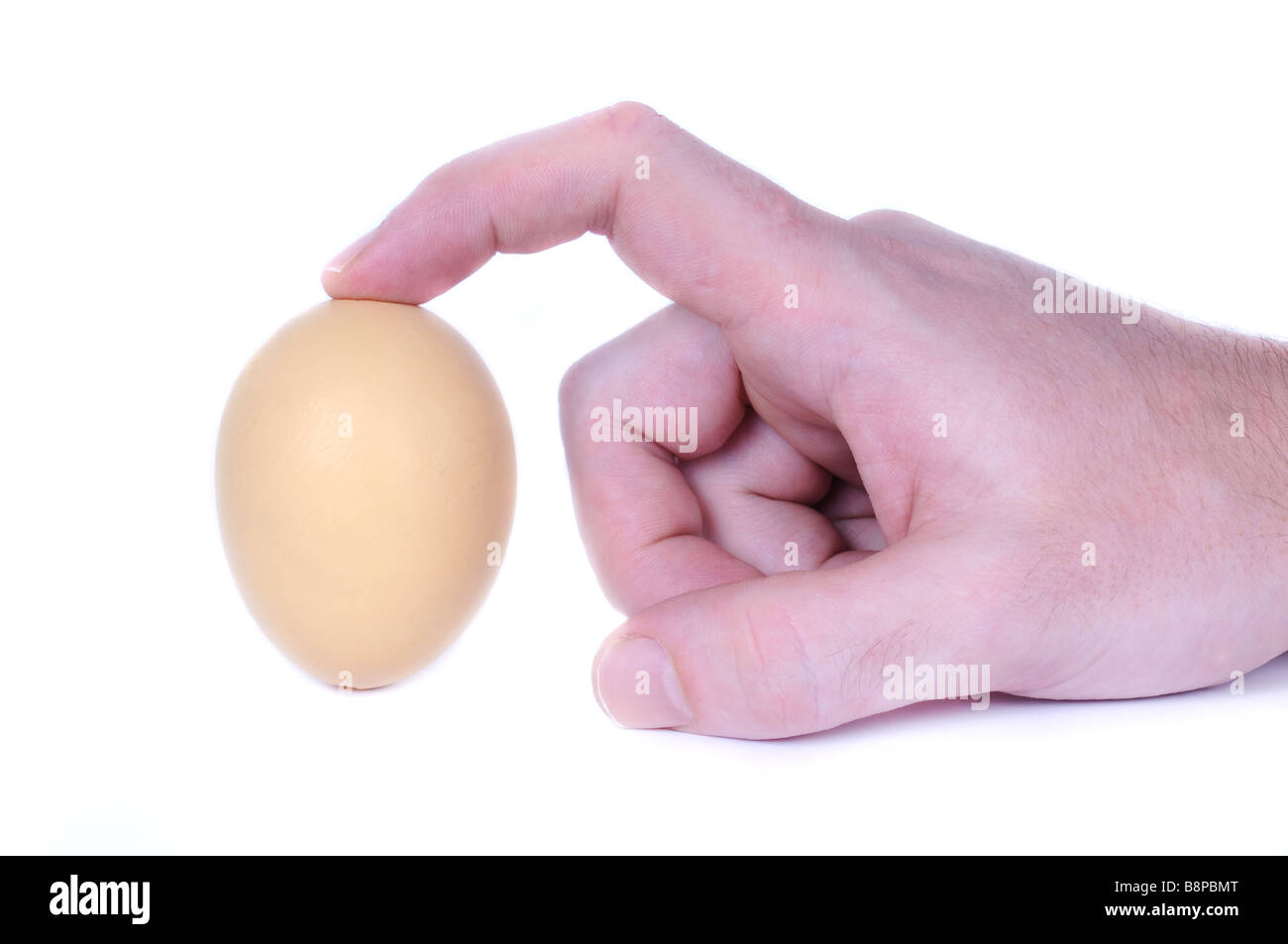 The Egg of Columbus - hand trying to make an egg stand on the tip. Stock Photo