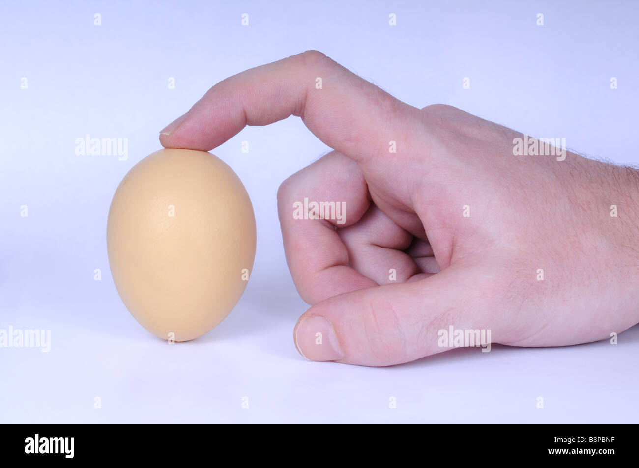 The Egg of Columbus - hand trying to make an egg stand on the tip. Stock Photo