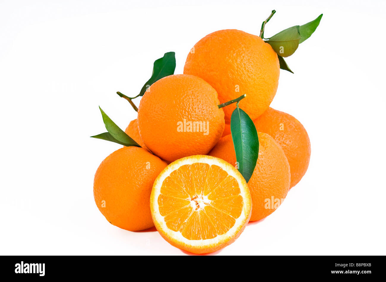 Pile of fresh juicy oranges with green leaves isolated on white background and one cut orange Stock Photo
