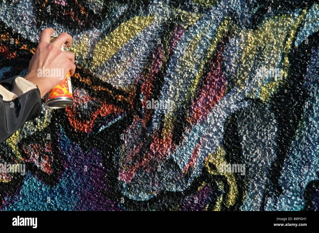 Hand of Graffiti artist using spray paint can and painting wall mural Stock Photo